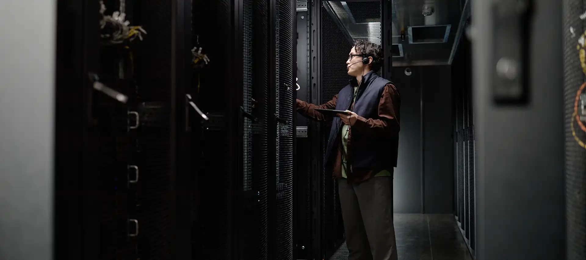 A man in a data center carefully inspecting the contents of a server rack