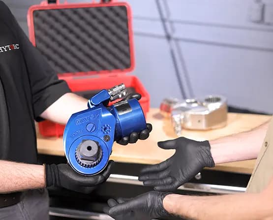 Two people exchanging an old, worn-down tool for a shiny new MXT+ Hydraulic Torque Wrench