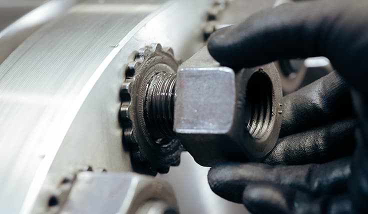 A gloved hand threads a nut down onto the HYTORC TRUE-LOCK Reaction Washer