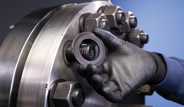 A gloved hand installing a TRUE-LOCK Washer on a bolt