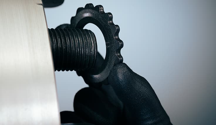 A gloved hand holding a HYTORC Washer, about to place it on a bolt