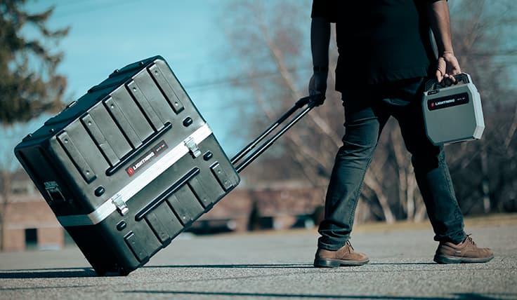 A person pulling the LIGHTNING Standard Battery-Operated Hydraulic Pump using the wheeled transportation case.