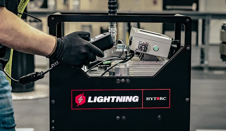 A side view of the LIGHTNING Smart Battery-Operated Hydraulic Pump showing an operator using the vibration feedback remote.